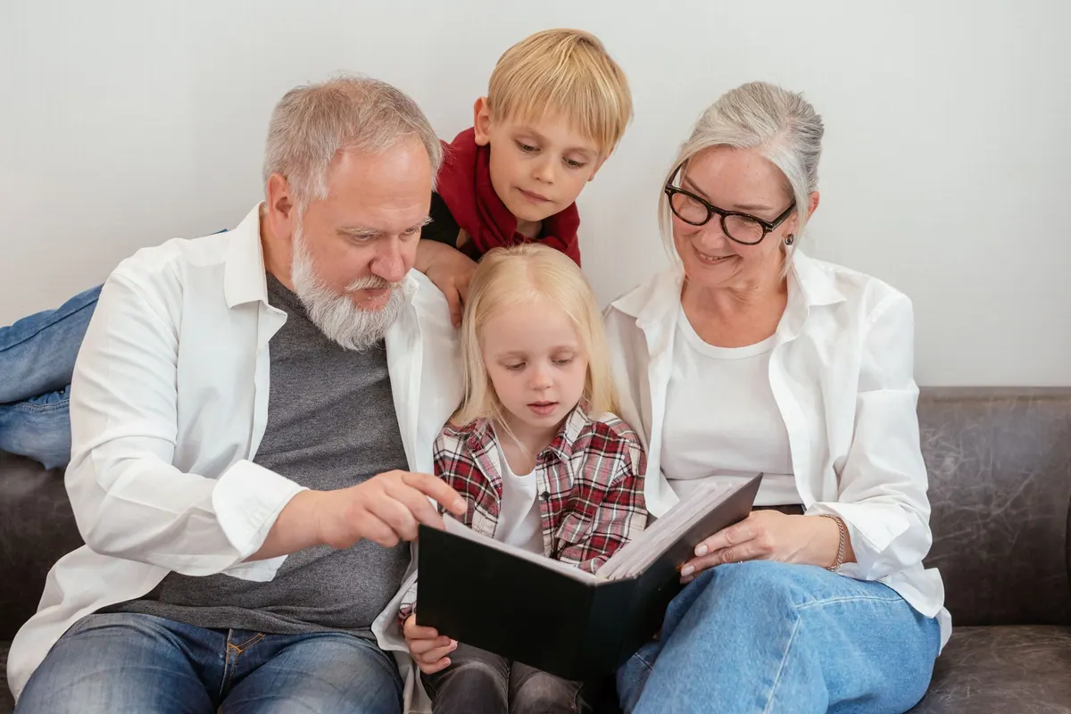 Grandparents and two grandchildren looking through a family photo album